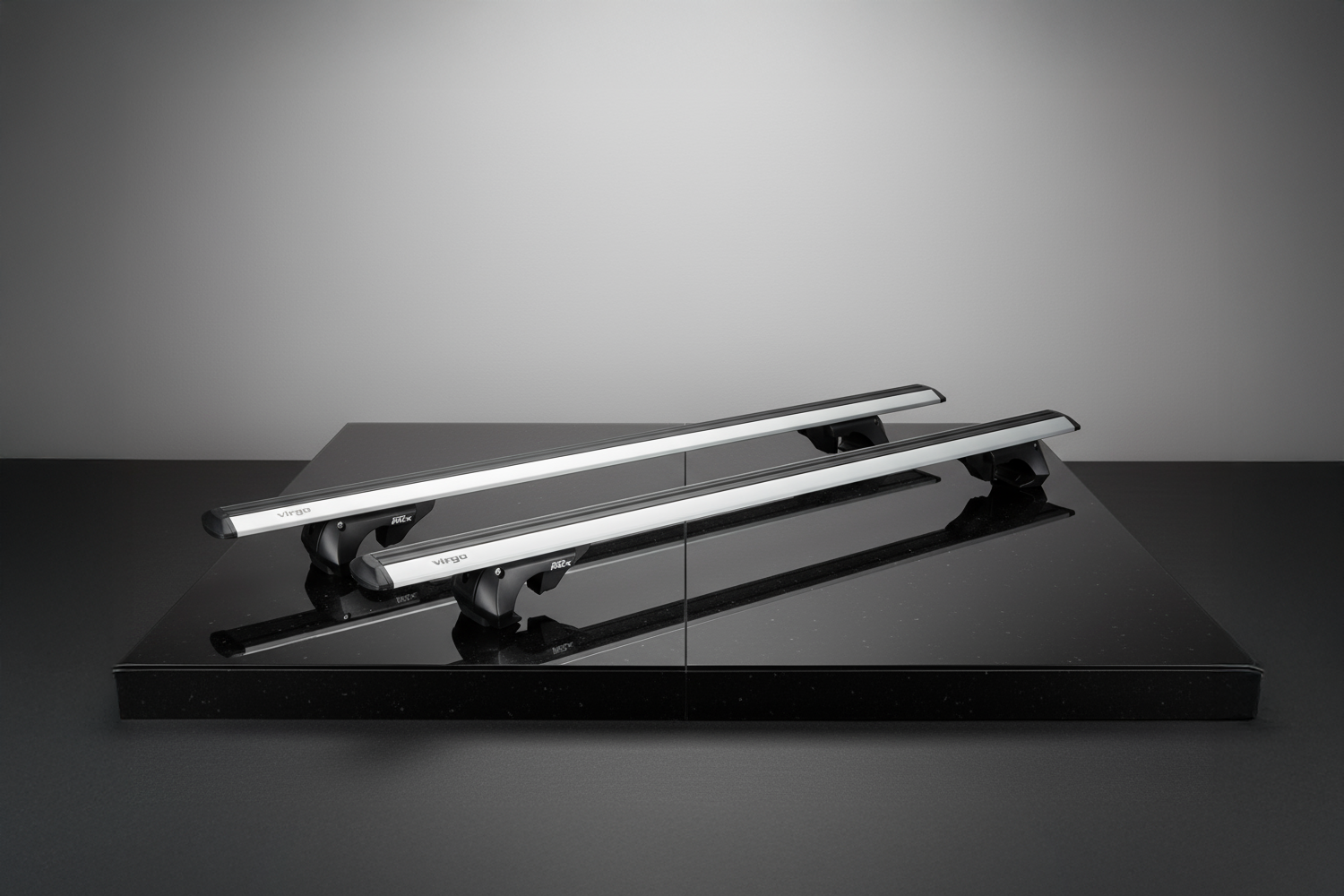 Silberne Dachreling des Basismodells, schräg angeordnet auf einer schwarzen, spiegelnden Oberfläche. Im Hintergrund eine weiße Wand. Punktförmiges Licht, das auf das Produkt fällt und einen Vignetteneffekt erzeugt.