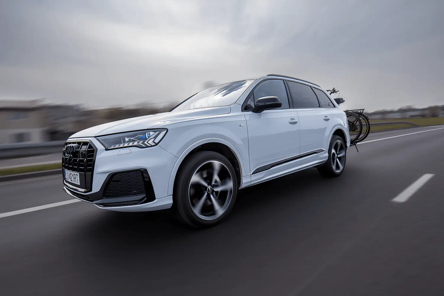 Weißer Audi SUV in Fahrt auf der Autobahn mit einem beladenen Heckfahrradträger auf der Anhängerkupplung.
